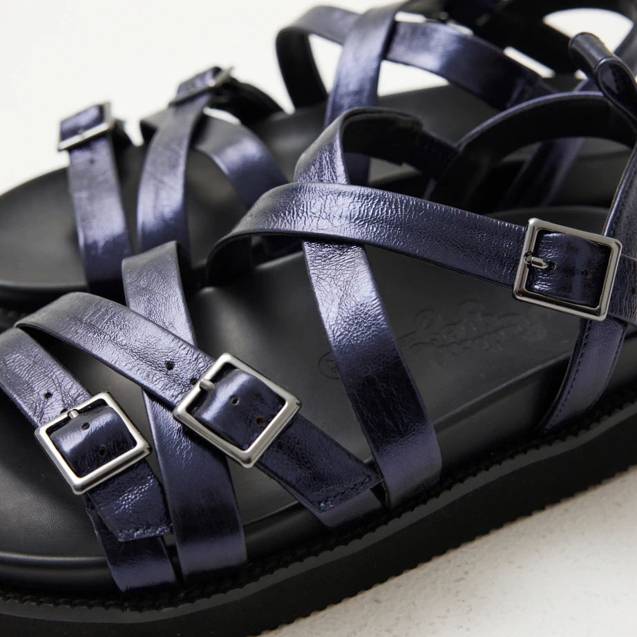 Close up of strappy summer sandals in navy blue metallic leather with silver buckles and arch support.