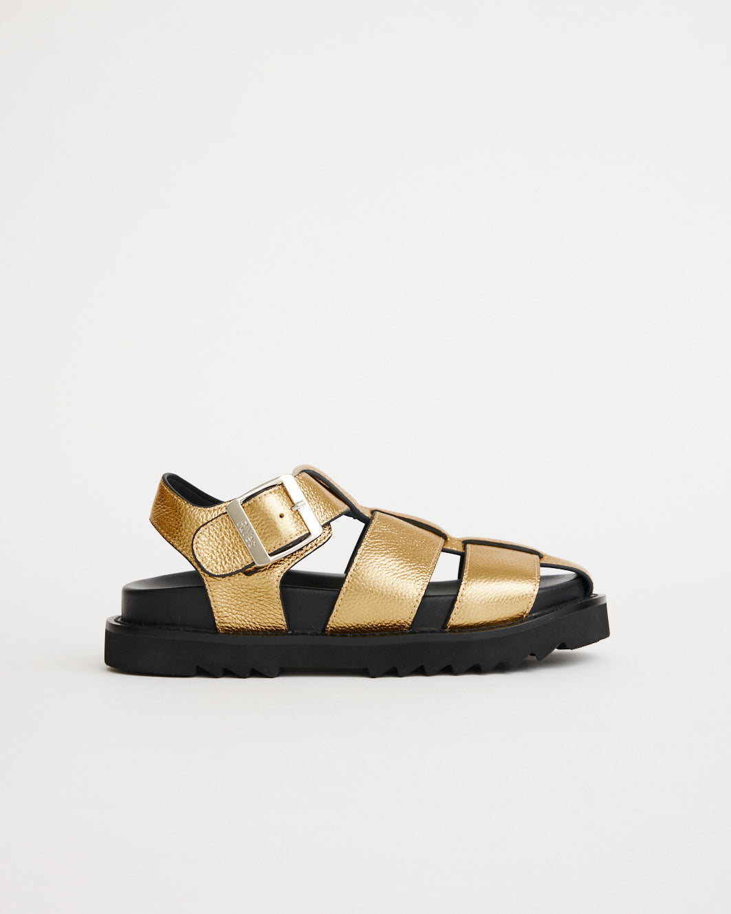 Gold sandal with black sole on a light gray background