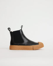 Black leather wool-lined Chelsea boot with brown sole on a white background