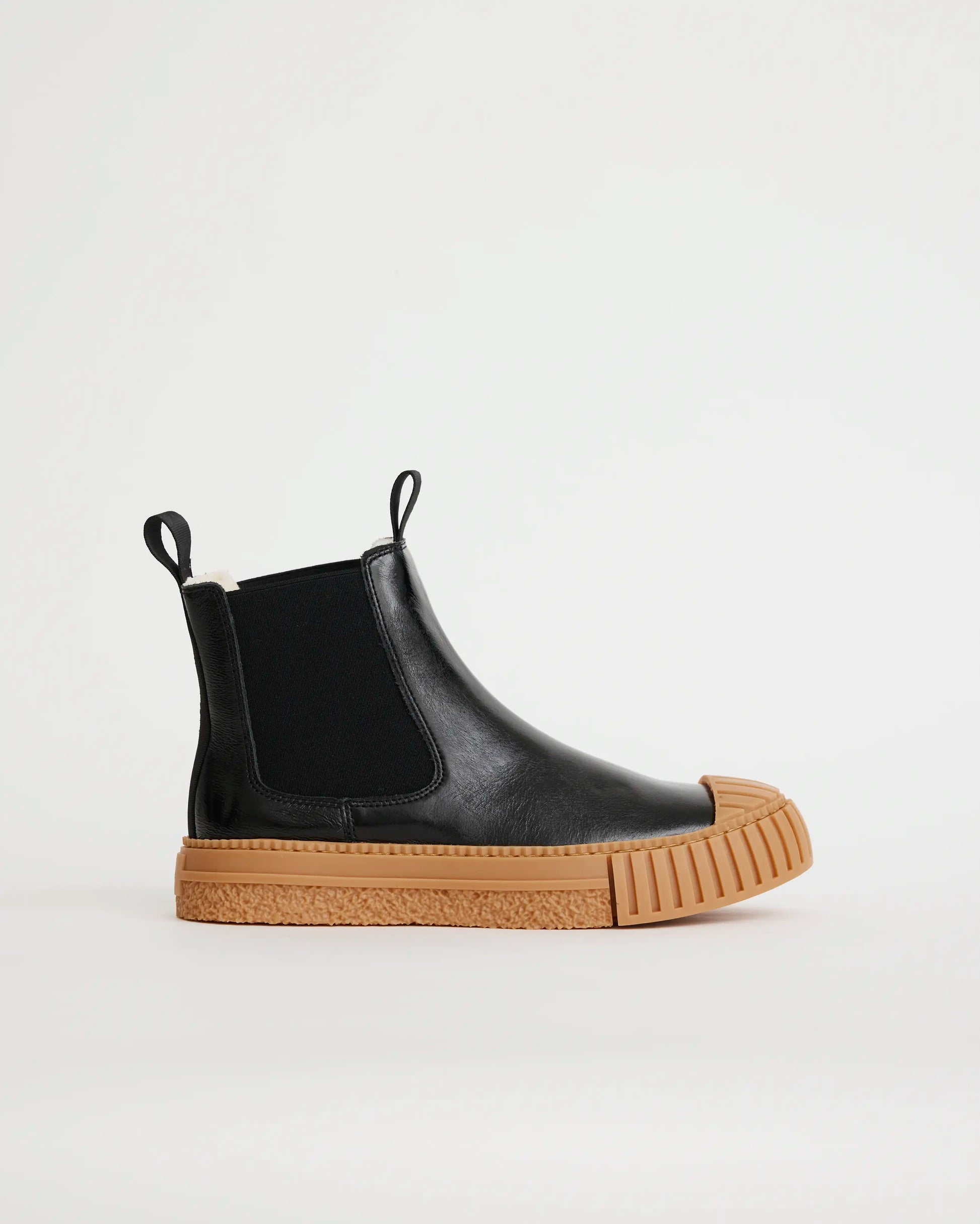Black leather wool-lined Chelsea boot with brown sole on a white background