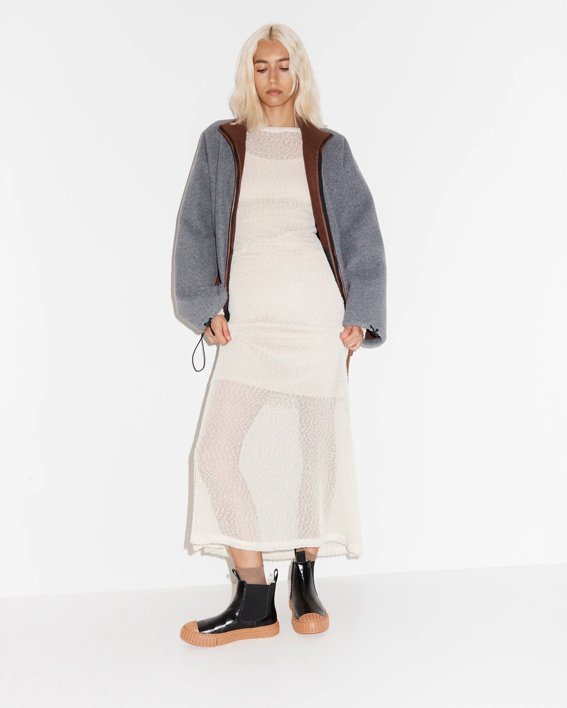 Person wearing a long sheer dress with black leather chelsea boots with a gum sole