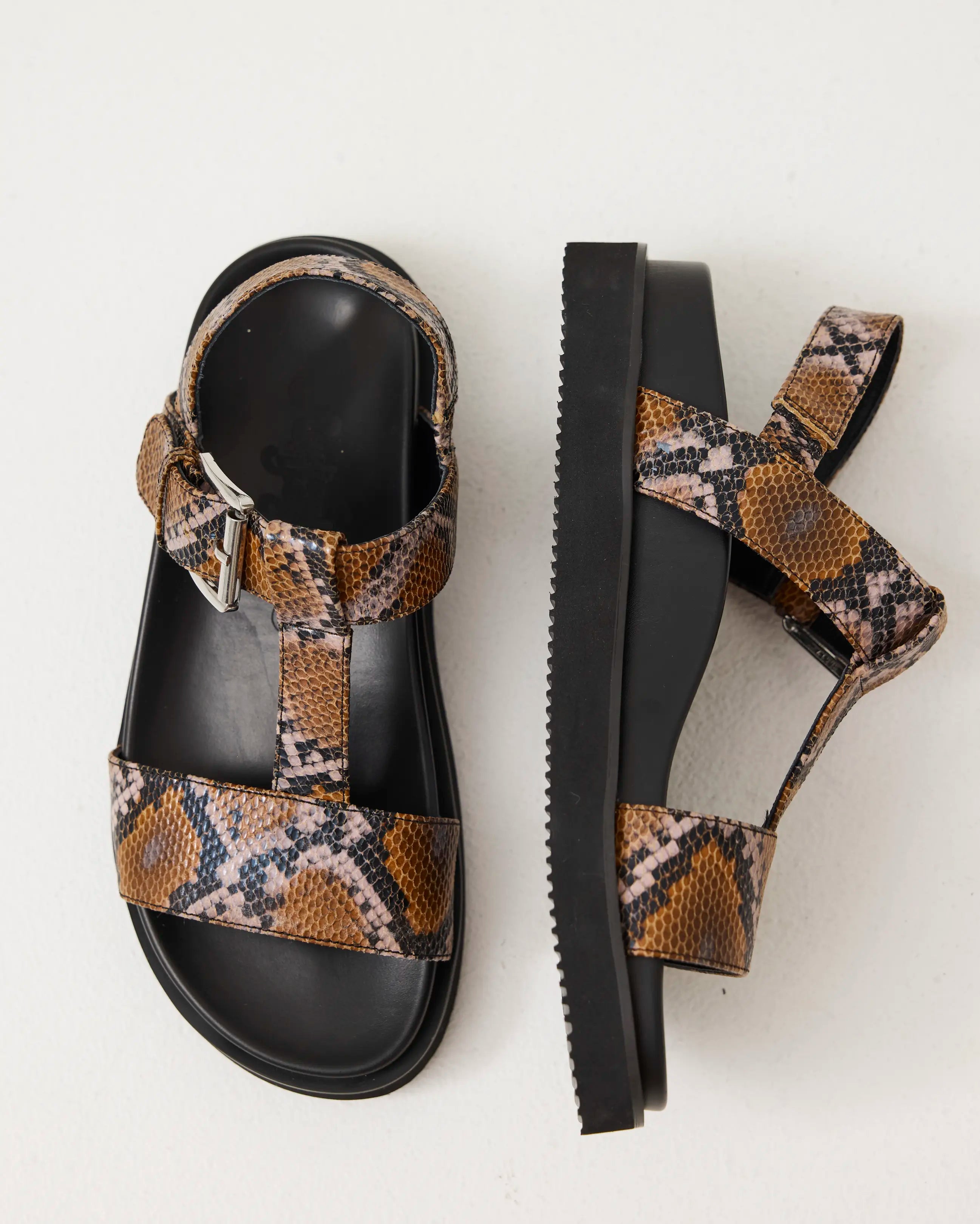 Arch support T-bar sandals with caramel snake print straps on a light gray background
