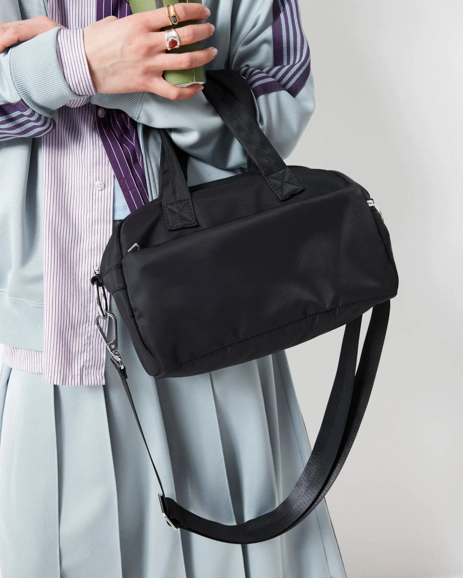 Person holding a black nylon bowling bag with a plain background