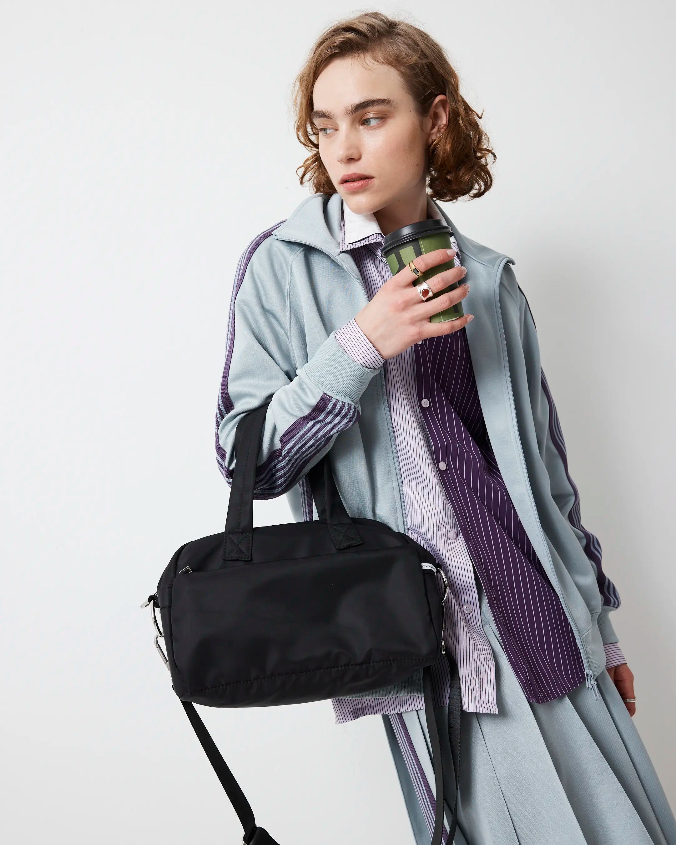 Person holding a black nylon bowling bag and a green cup