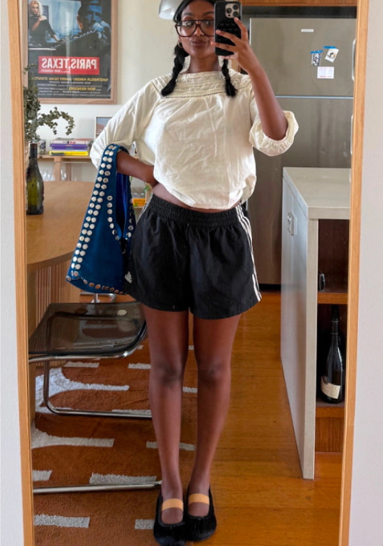 Person wearing black shorts with black leather ballet flats