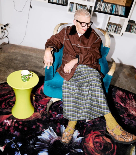 Person wearing a plaid skirt and yellow socks with snake printed leather slingbacks