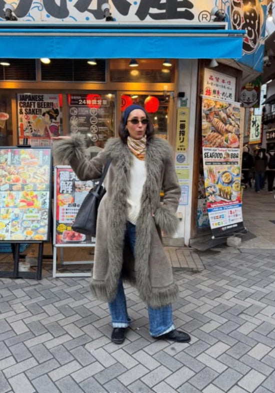 Person wearing a furry jacket with black leather boots