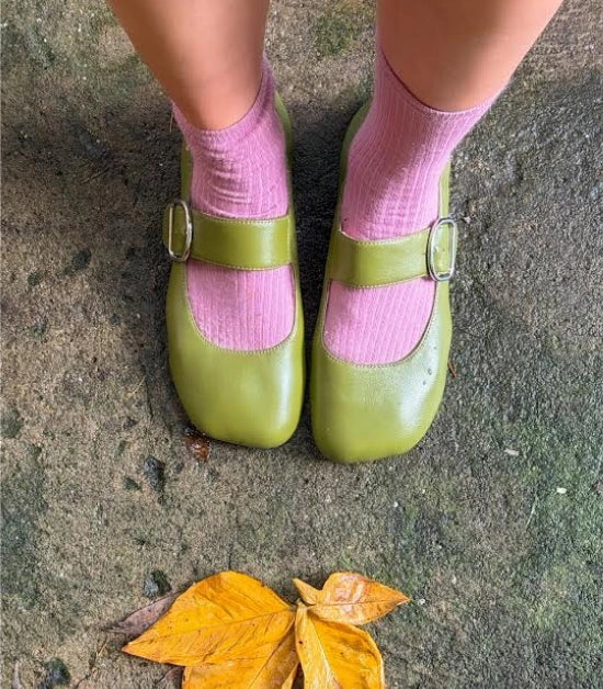 Person wearing pink socks with green leather ballet flats