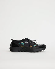 Black sneaker with floral design on a light gray background