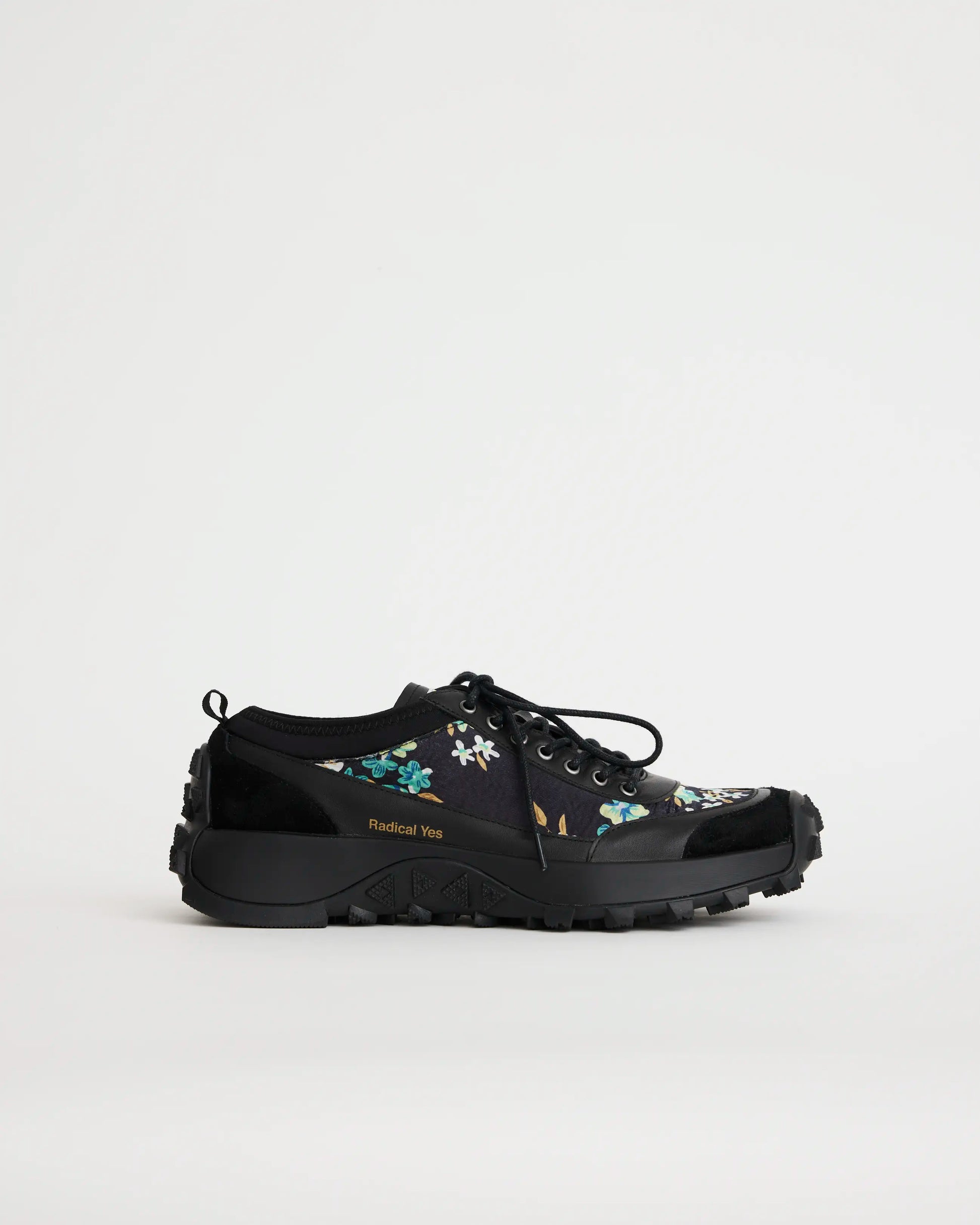 Black sneaker with floral design on a light gray background