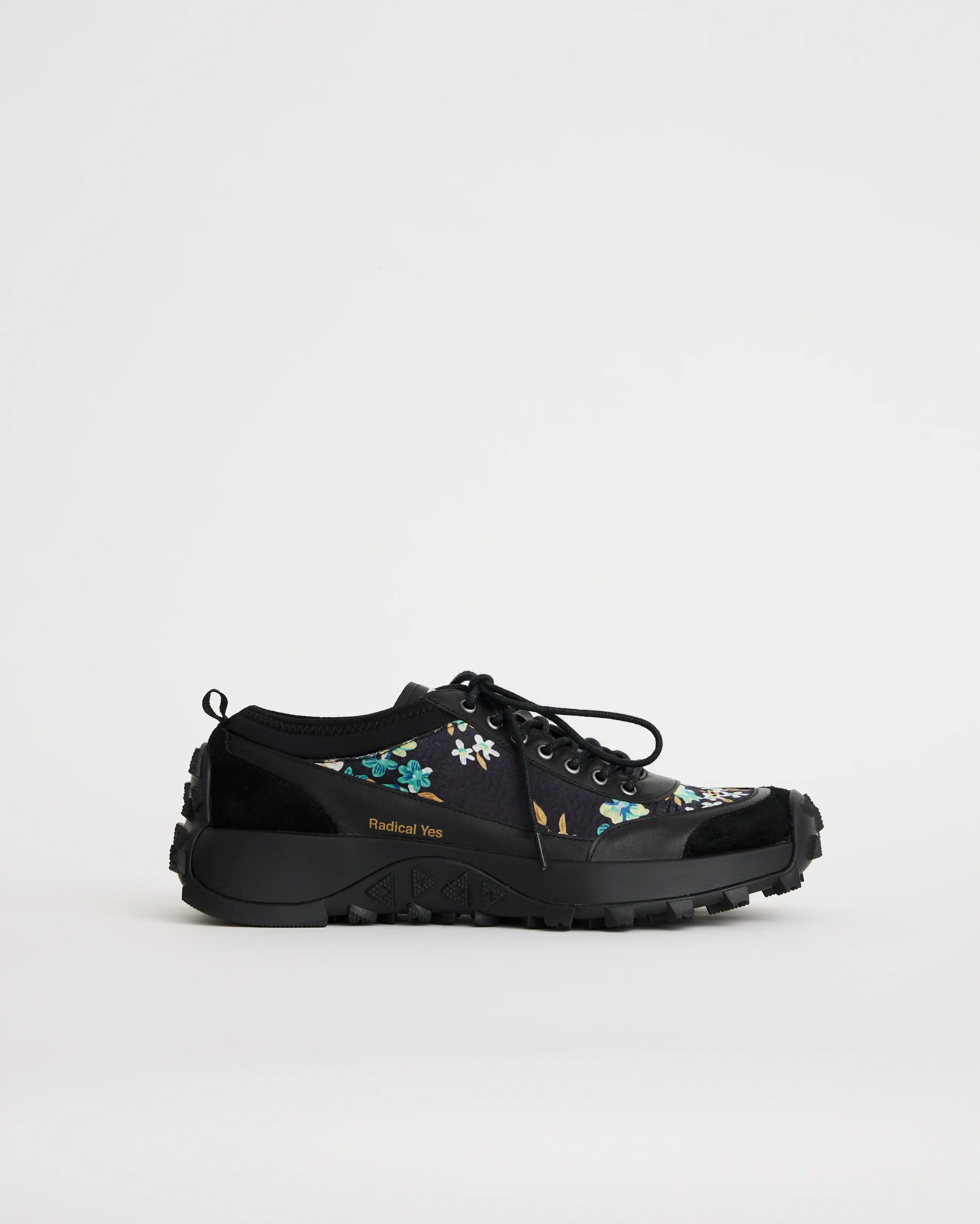 Black sneaker with floral design on a light gray background