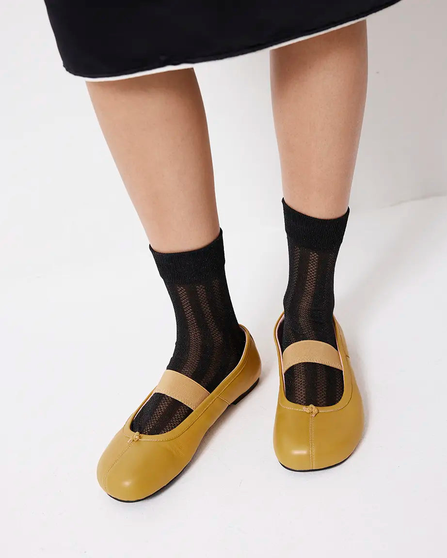 Yellow shoes worn with black socks on a white background