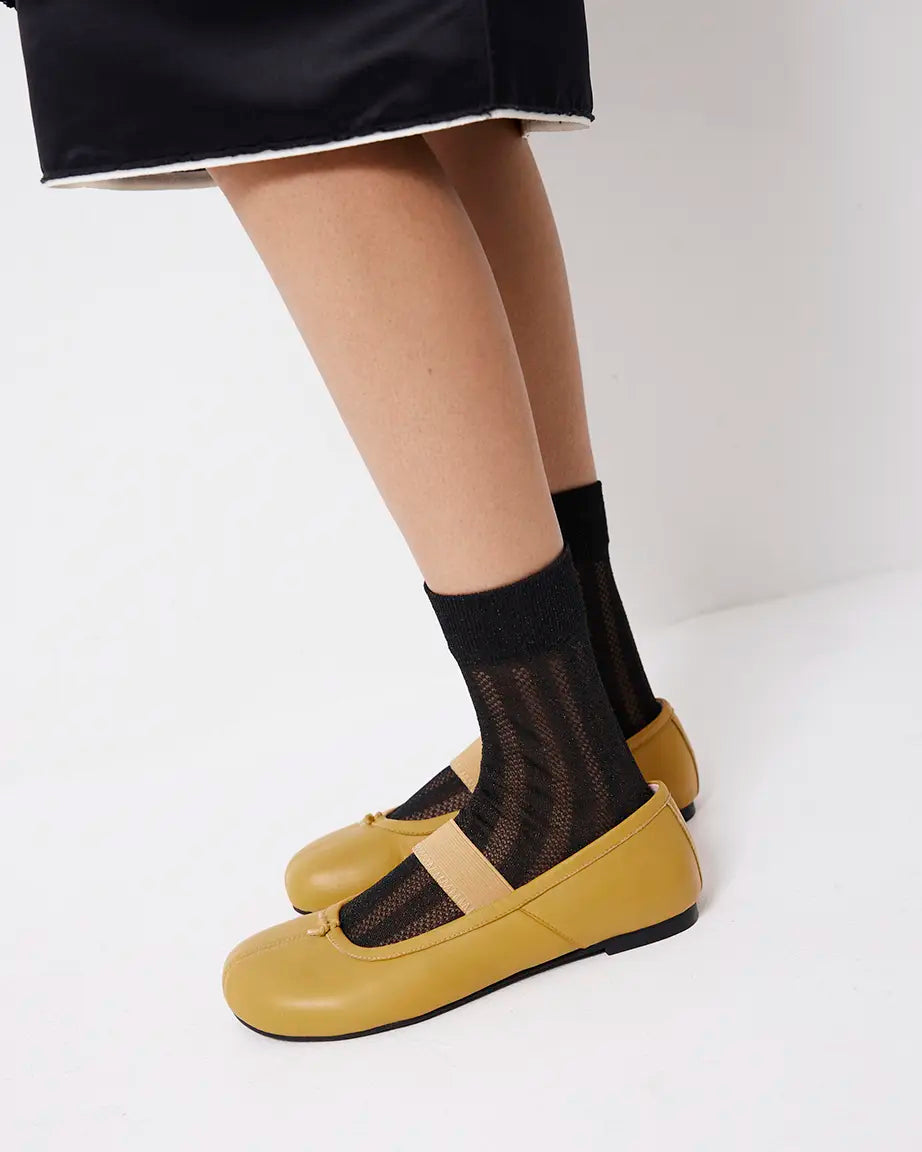 Yellow shoes worn with black mesh design socks on a white background