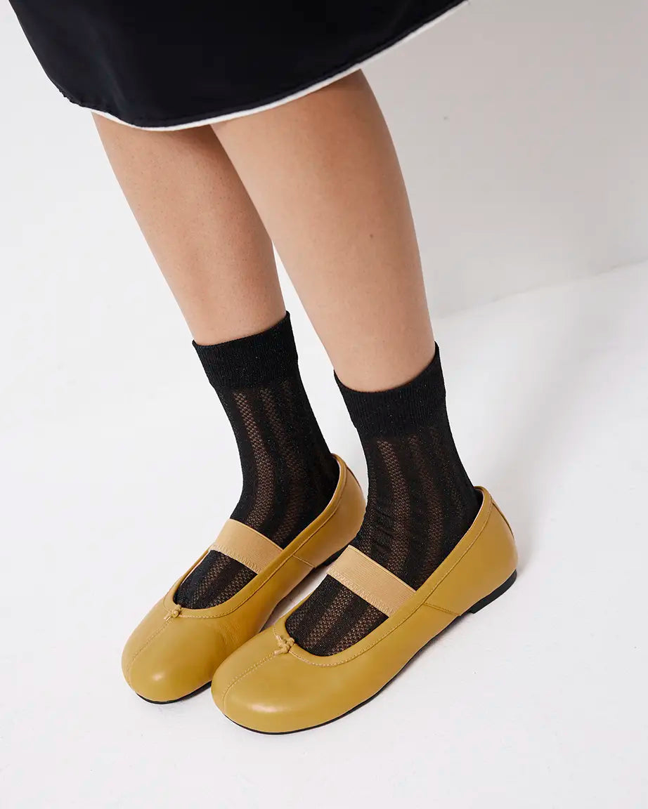 Yellow shoes with black mesh socks on a white background