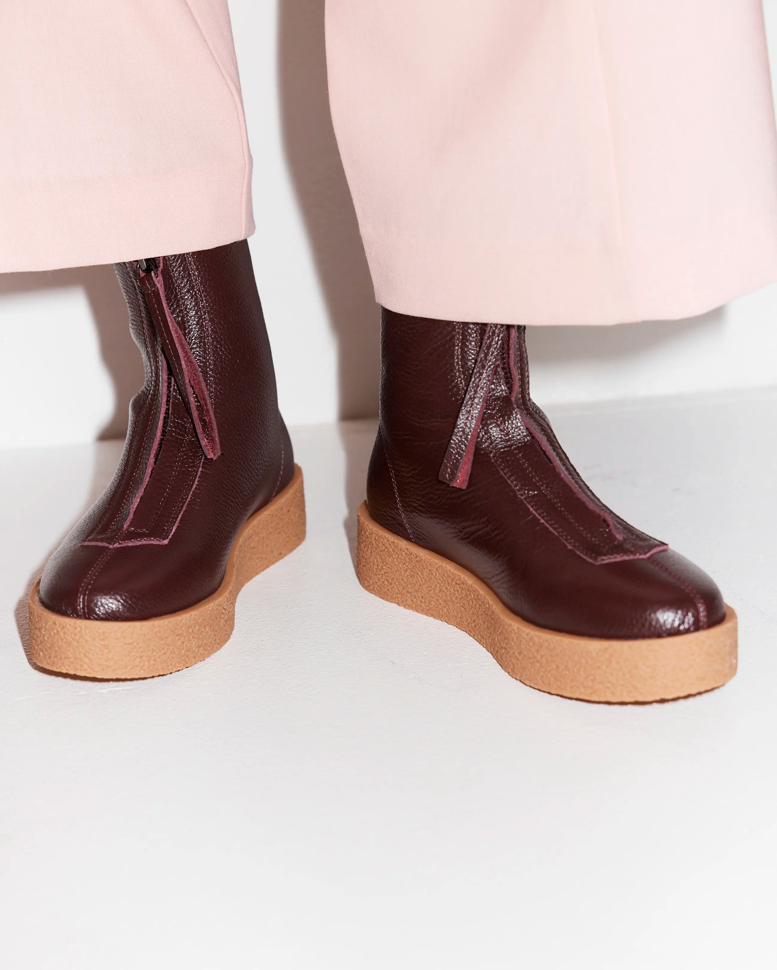 Purple zip front boots with tan soles worn with pink pants.