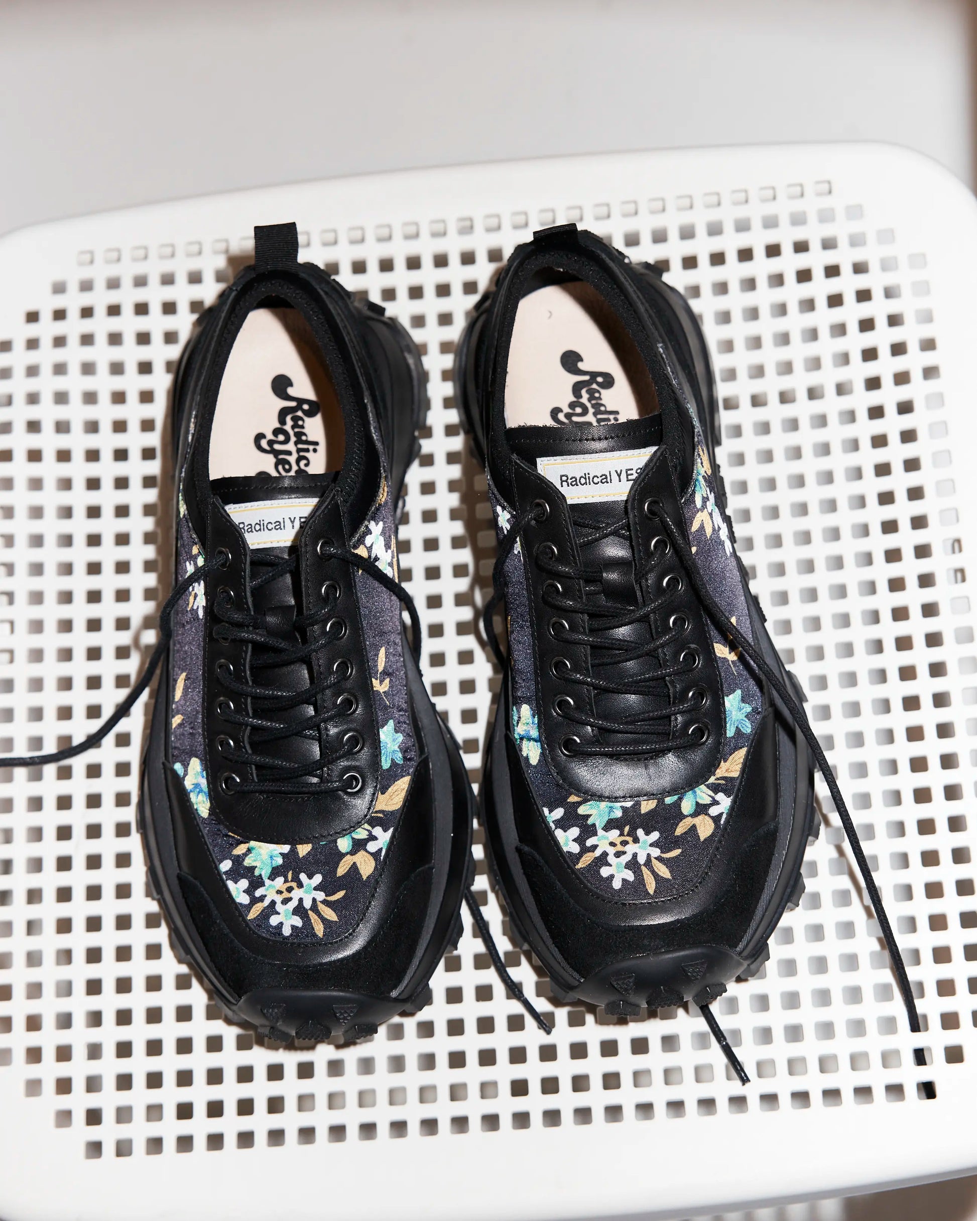 Pair of black sneakers with floral patterns on a white surface