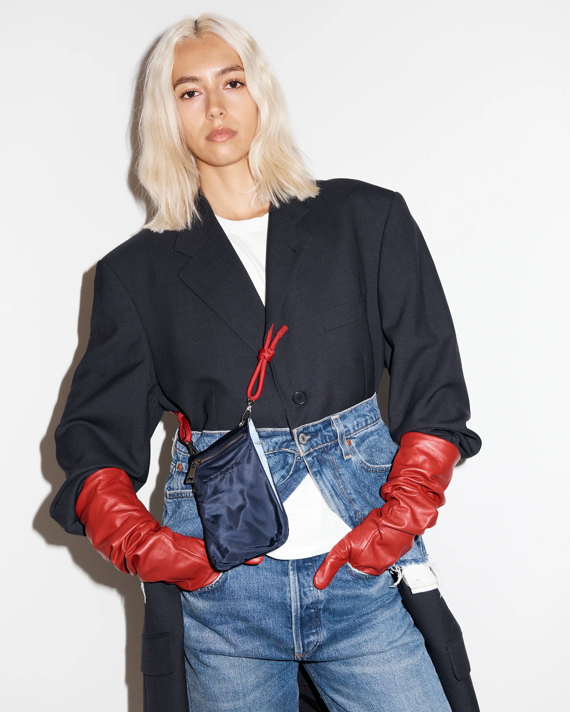 Person wearing a black jacket, red gloves and carrying a navy phone pouch with a red strap
