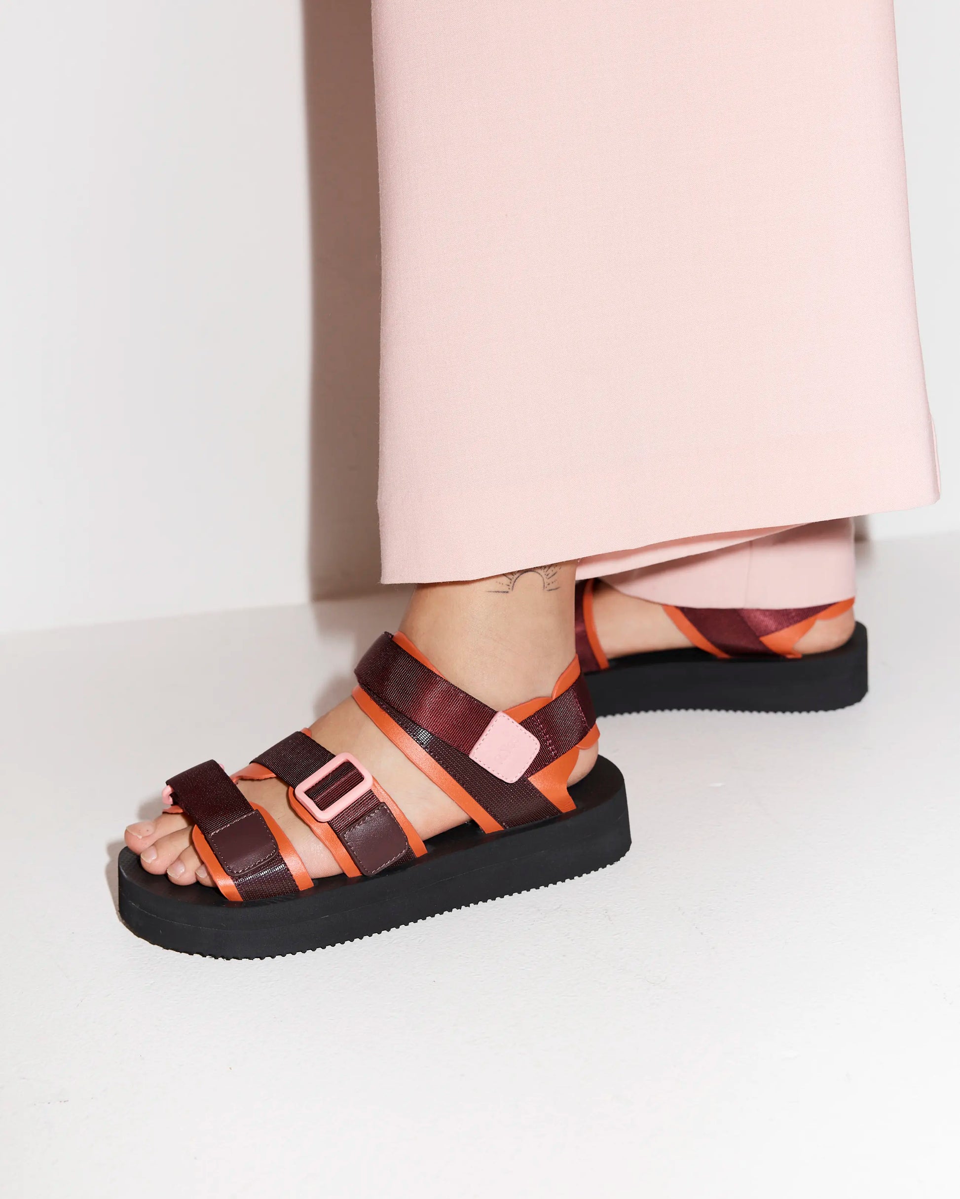 Person wearing cherry and mango athletic sandals with a white background