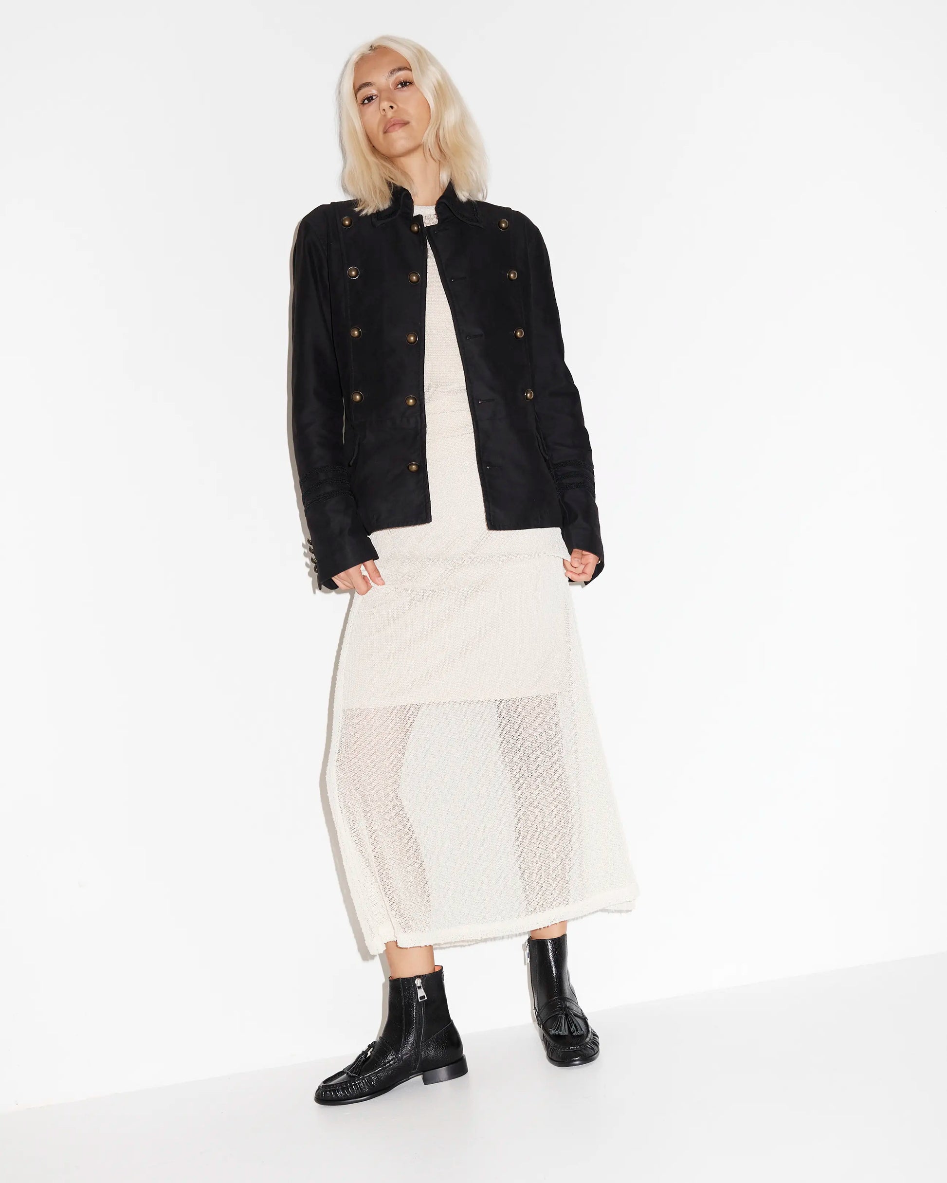Person wearing a black jacket and black leather boots on a white background