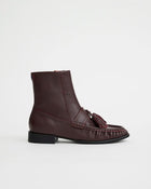 A cherry leather ankle boot with a tassel detail across the vamp and a low black block heel.
