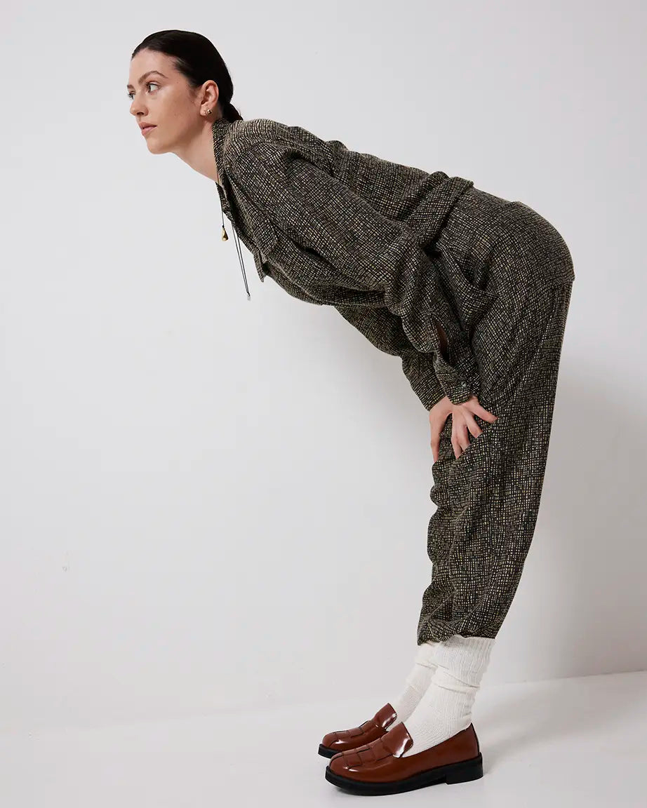 Person wearing a textured outfit with brown leather loafers on a white background