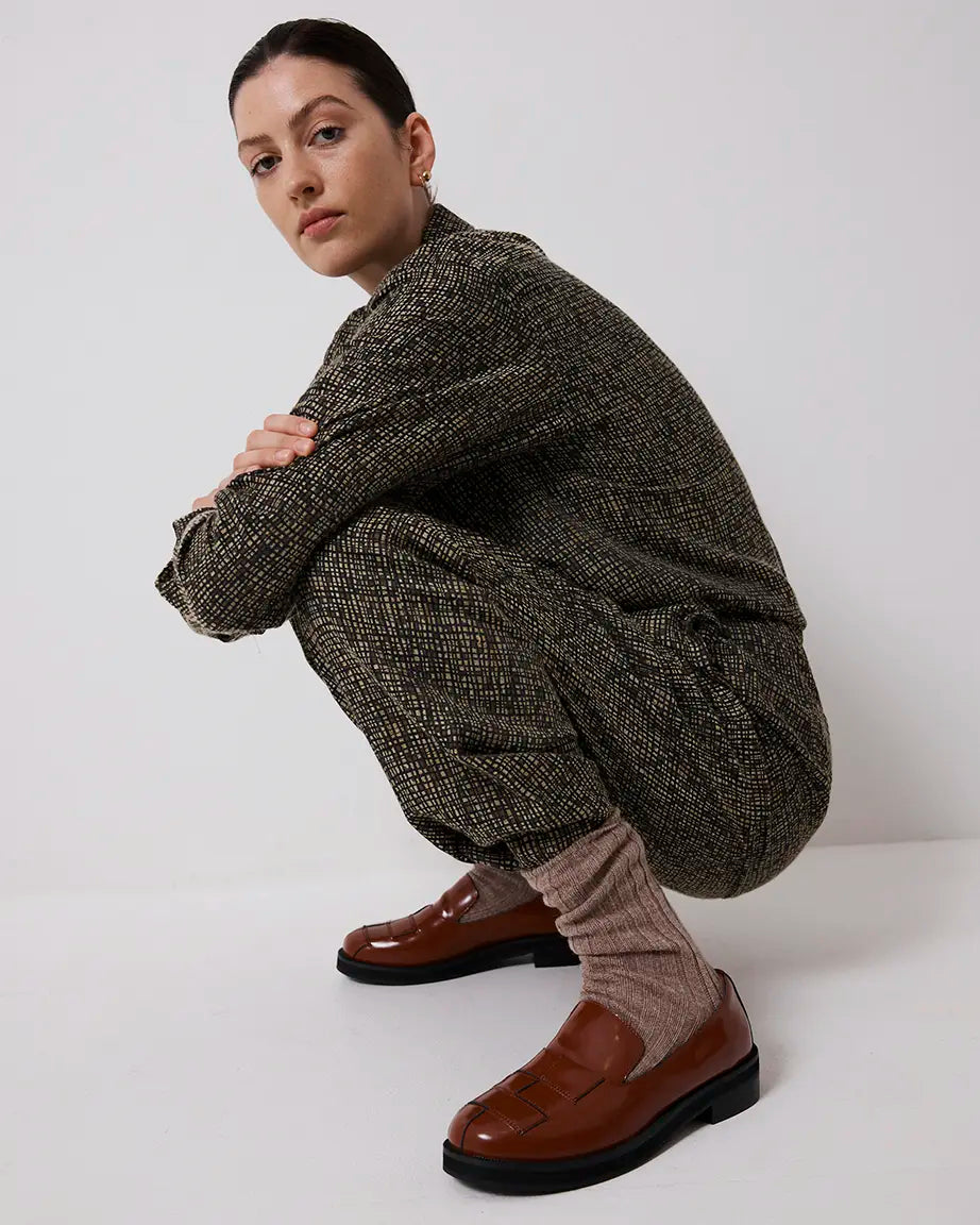 Person wearing a textured sweater and brown leather loafers on a white background
