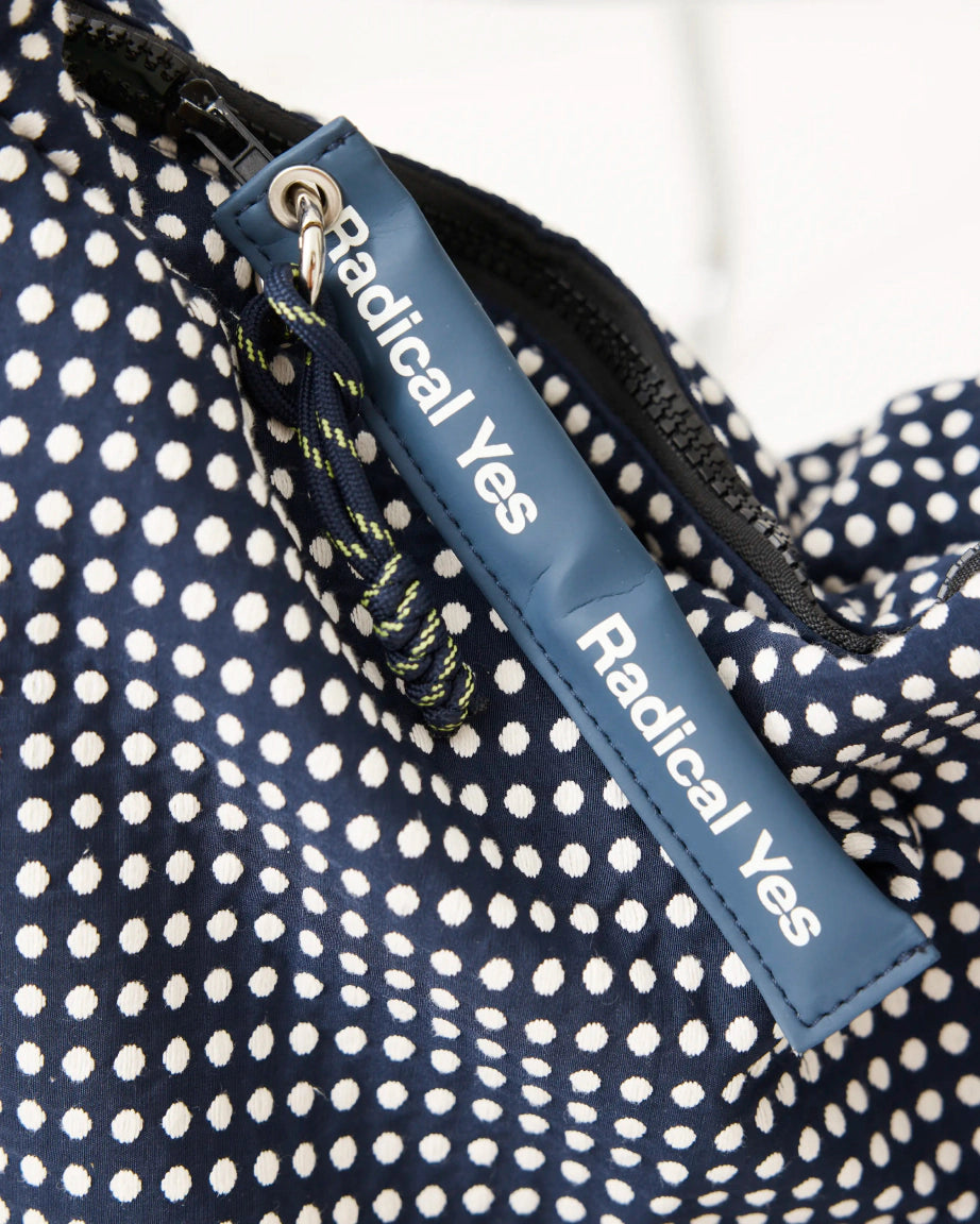 Blue strap with 'Radical Yes' text on a polka dot fabric background