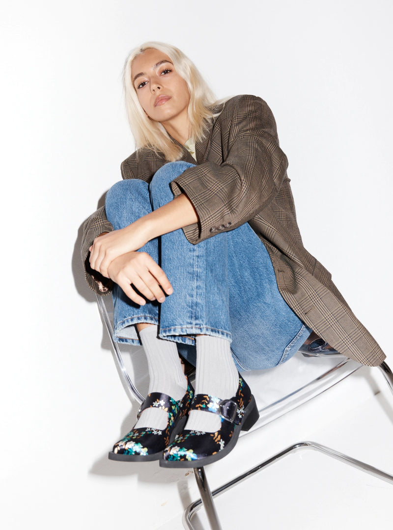 A woman wearing a plaid blazer with floral printed navy square toe mary janes