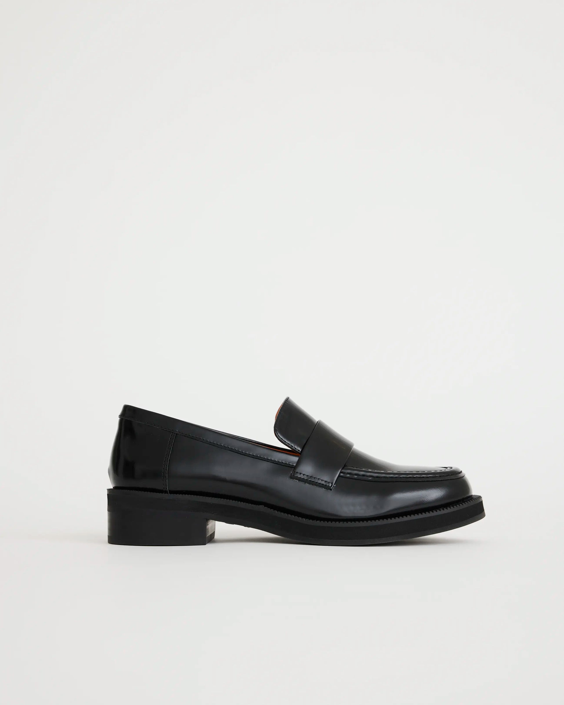 Black leather loafers on a light gray background