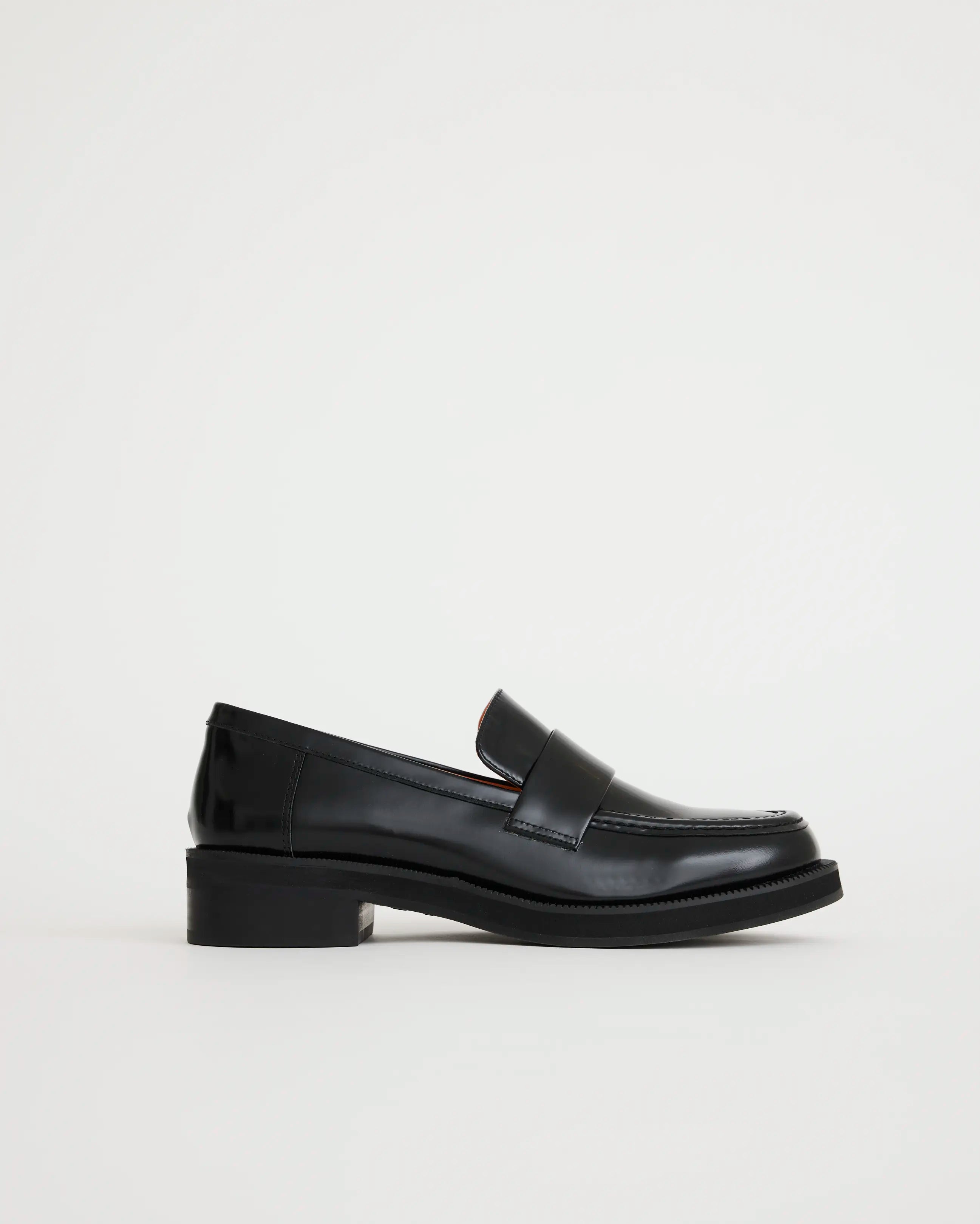 Black leather loafers on a light gray background