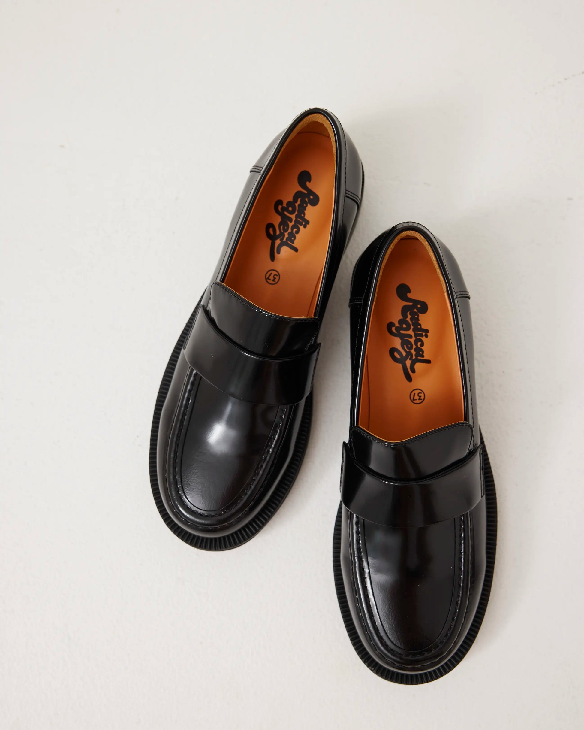 Pair of black leather loafers on a light gray background