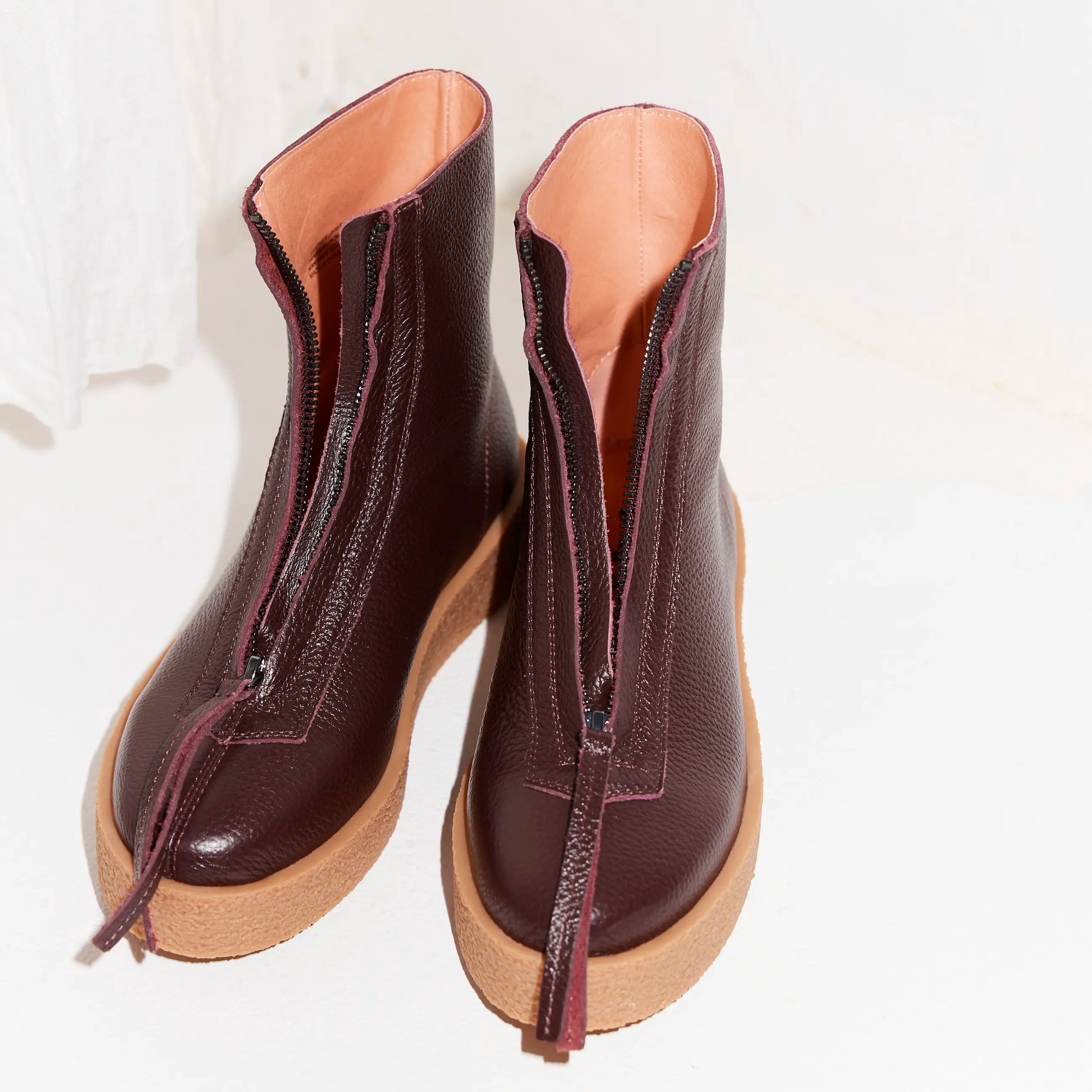 Pair of purple leather ankle boots with brown soles on a white background