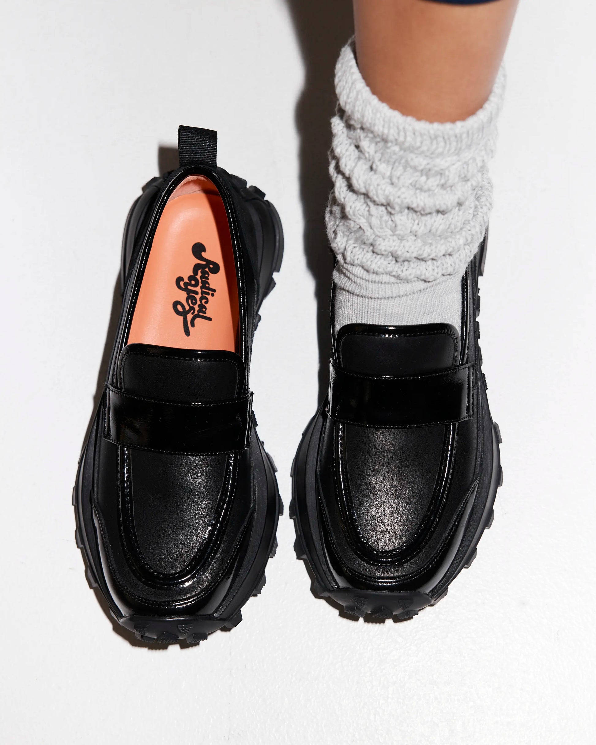 Black platform loafers worn with white socks on a light gray background