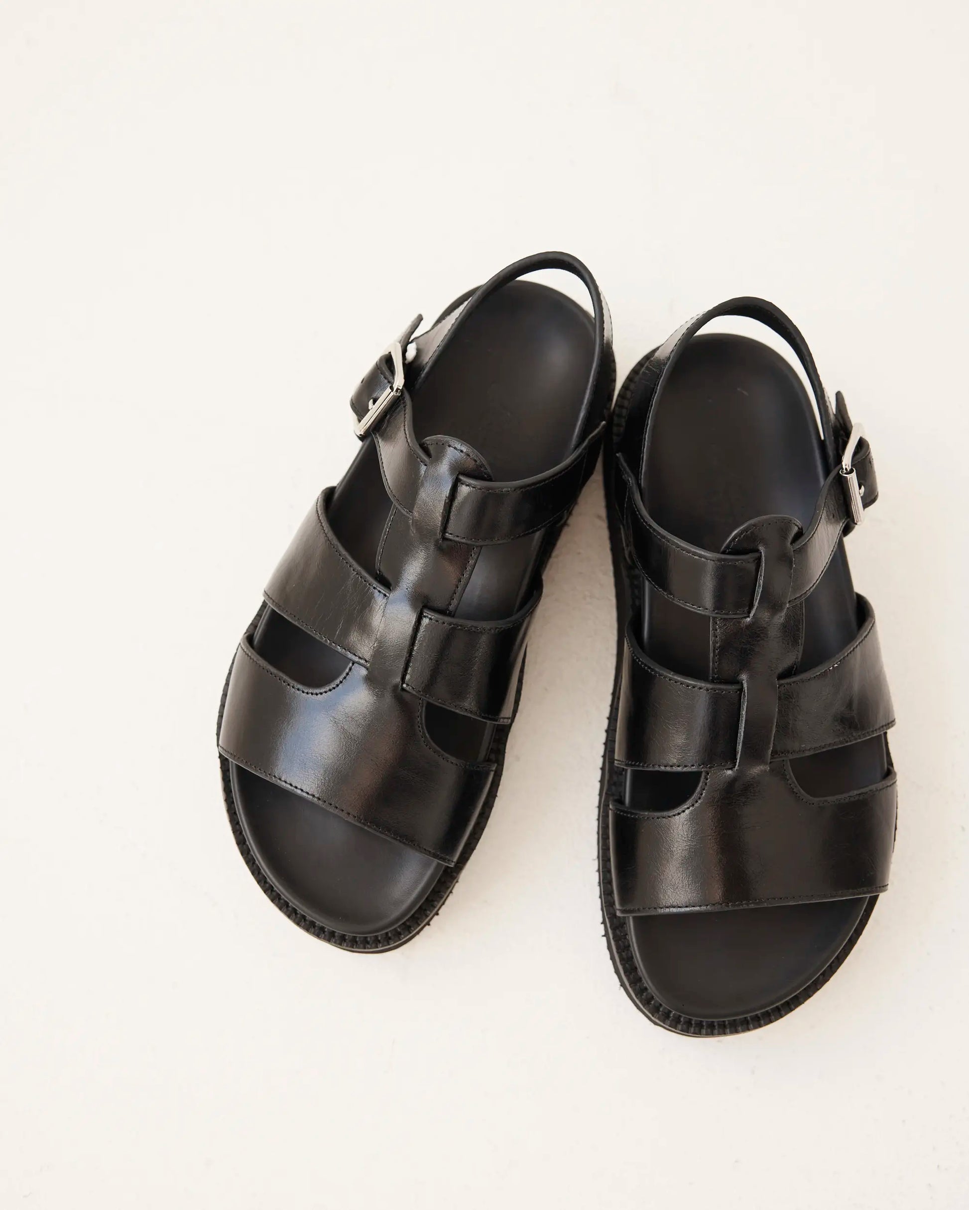 A pair of black leather strappy sandals with adjustable buckle straps