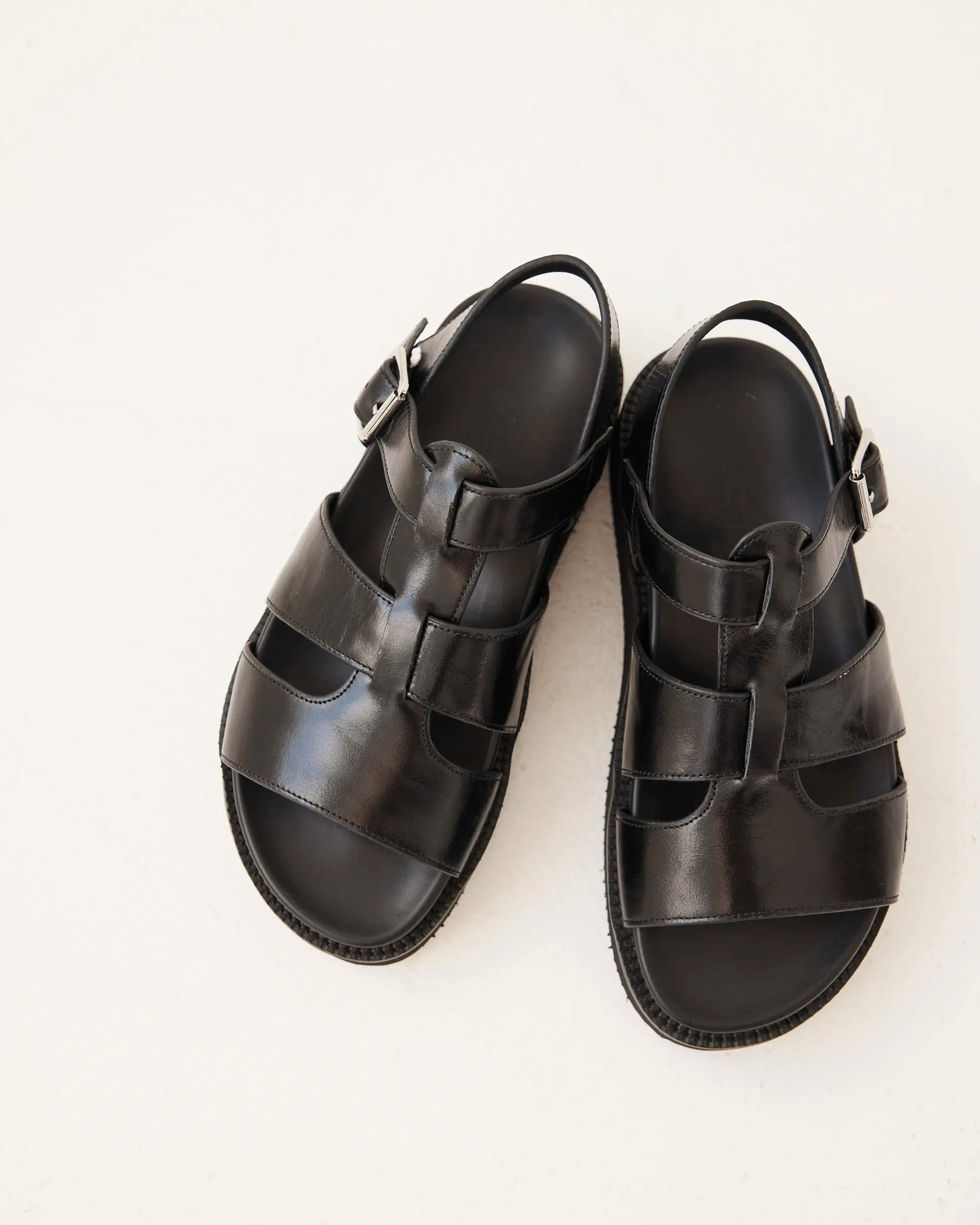 A pair of black leather strappy sandals with adjustable buckle straps