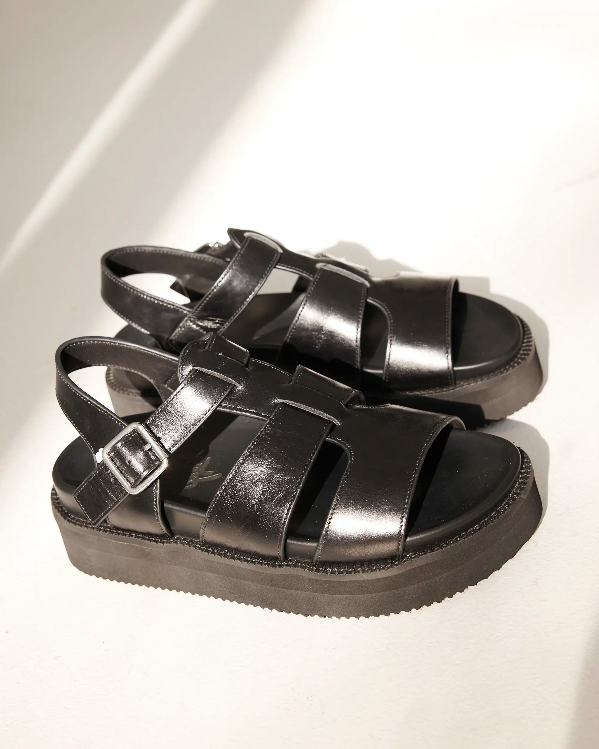 A pair of black leather strappy platform sandals with buckle straps