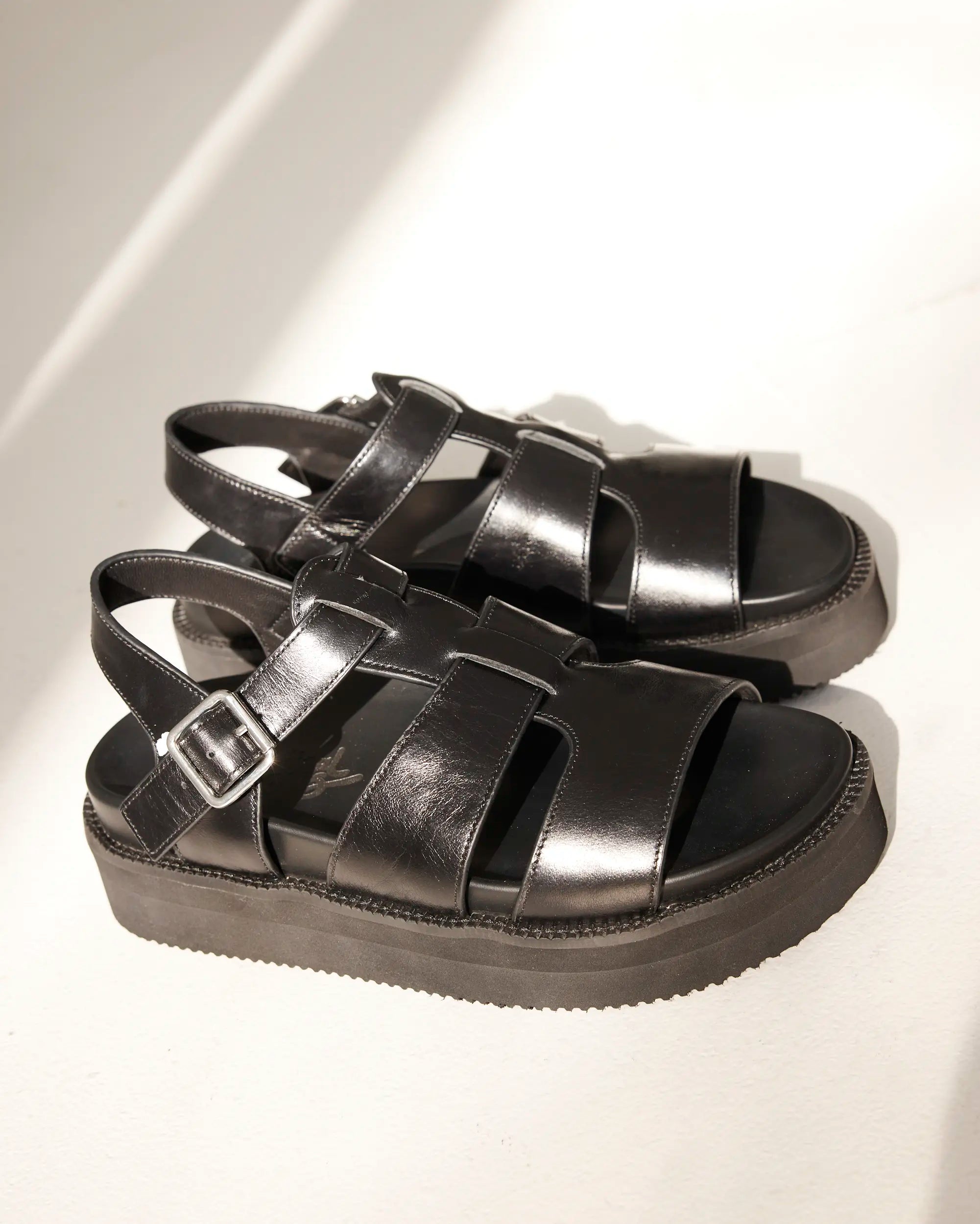 A pair of black leather strappy platform sandals with buckle straps