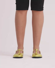 Person wearing gold flat shoes with black capris