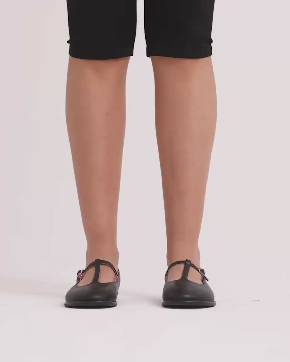 Load video: Person wearing black t-bar shoes against a white background