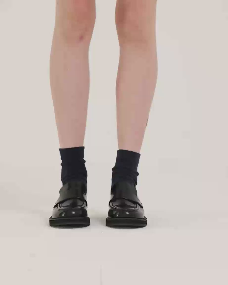 Load video: Person wearing black leather loafers with black socks.