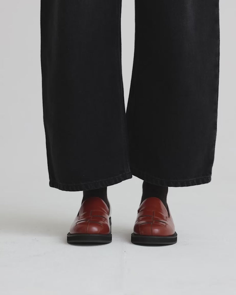 Person wearing brown leather shoes with black socks and black pants.