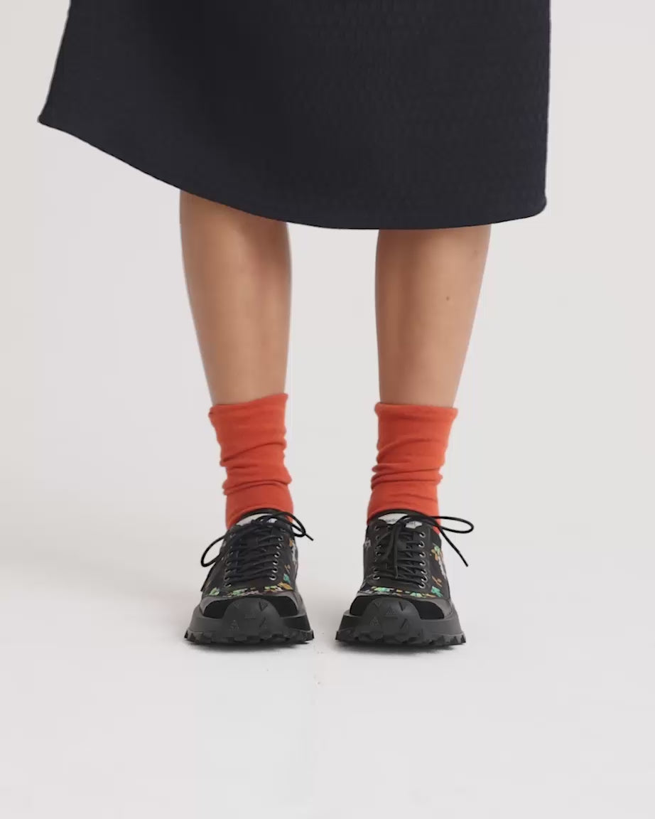 Load video: Person wearing black floral printed lace up sneakers with a chunky black sole