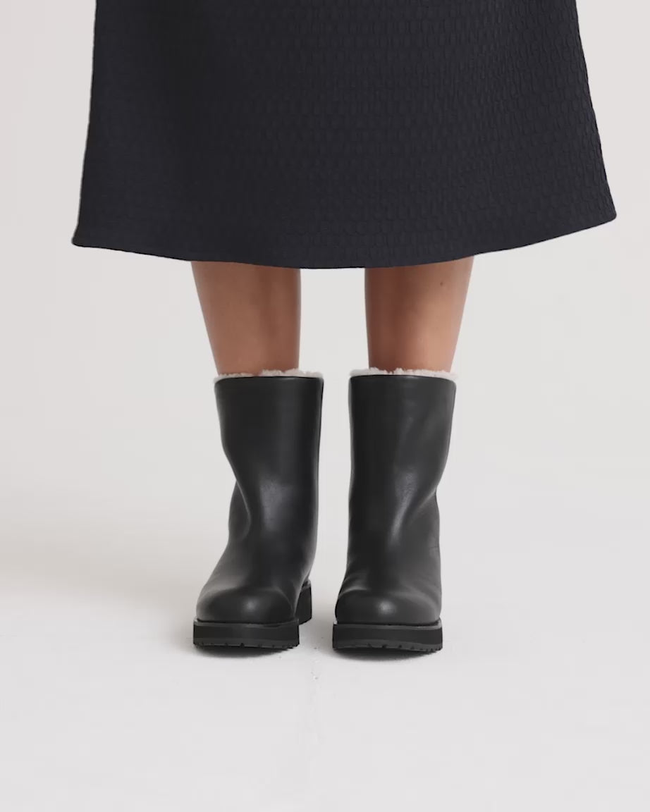 Load video: Person wear black leather wool-lined boots with a chunky black sole