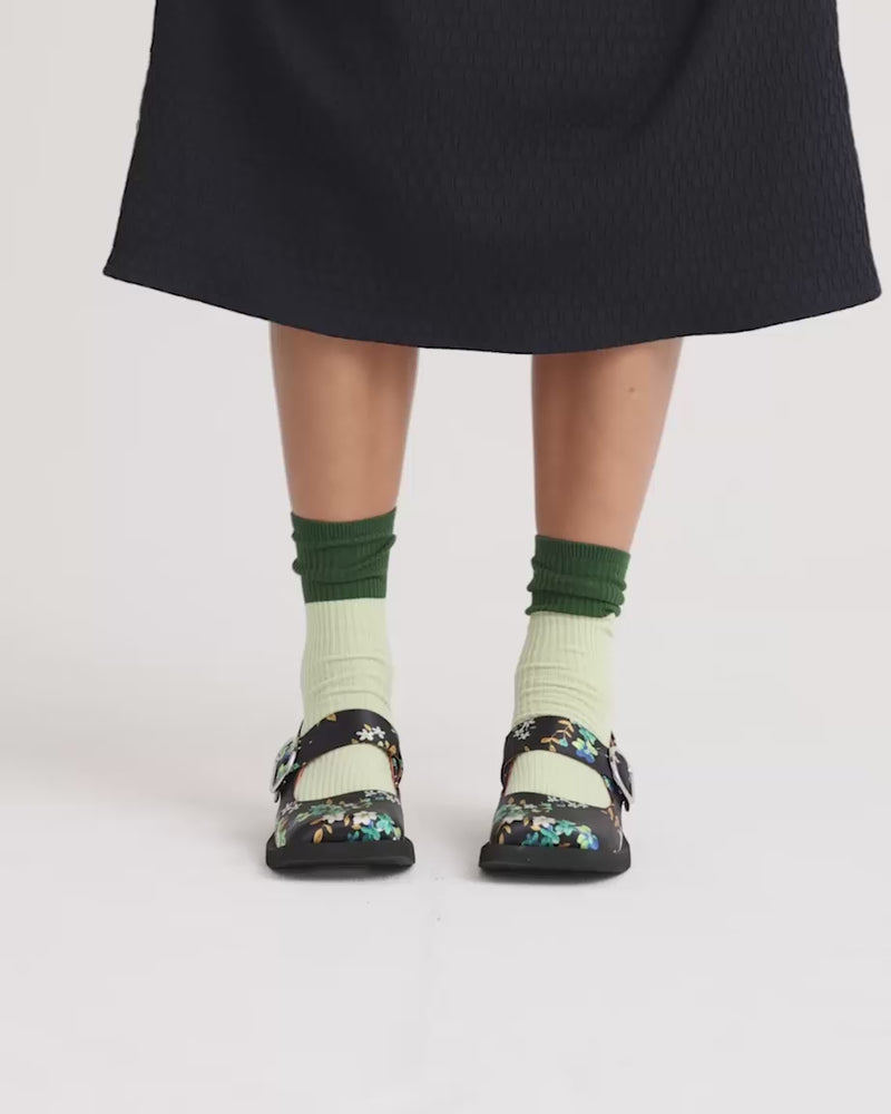 Person wearing navy floral printed satin square toe shoes with a silver buckle