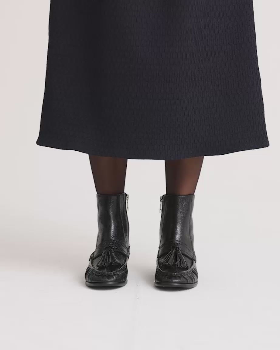 Load video: Person wearing black leather boots with tassels