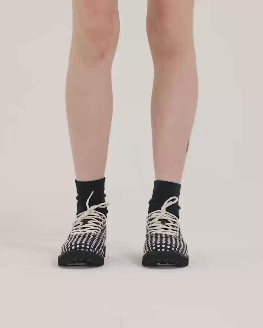 Load video: Person wearing navy and white polka dot shoes and black socks.