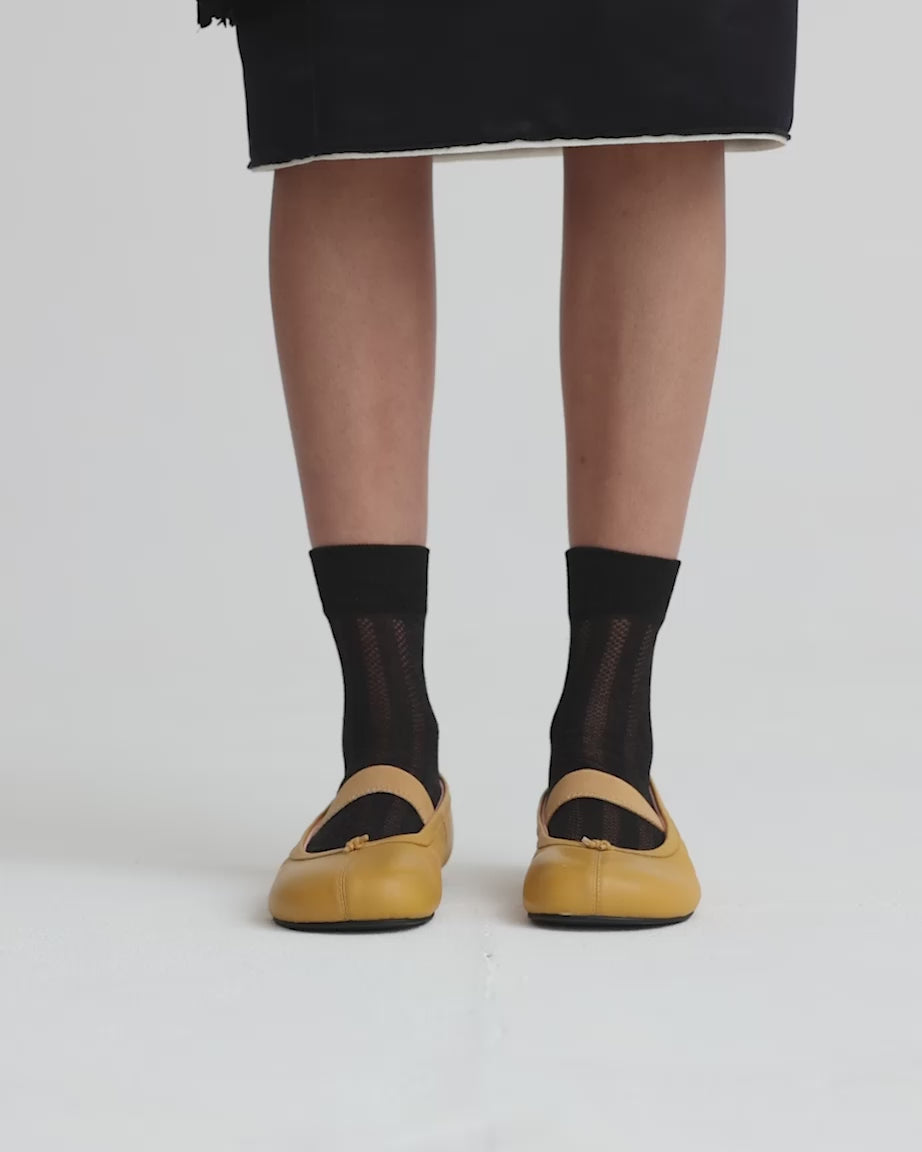 Load video: Person wearing yellow shoes with black mesh socks against a white backgroud