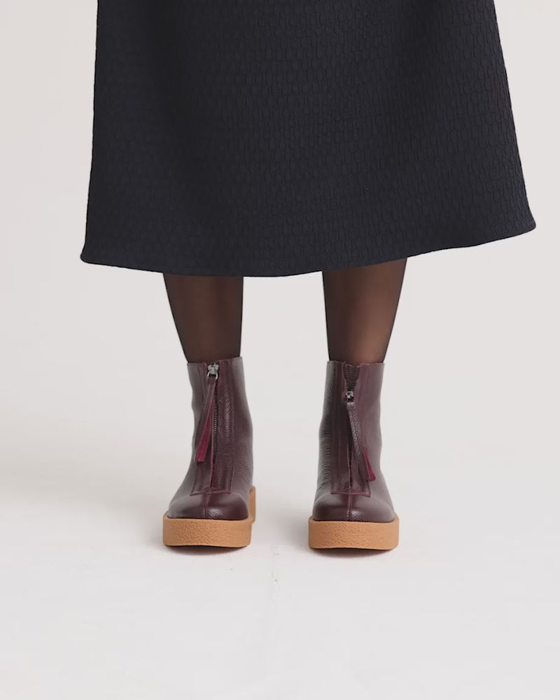 Purple zip front boots with tan soles worn with black stockings.