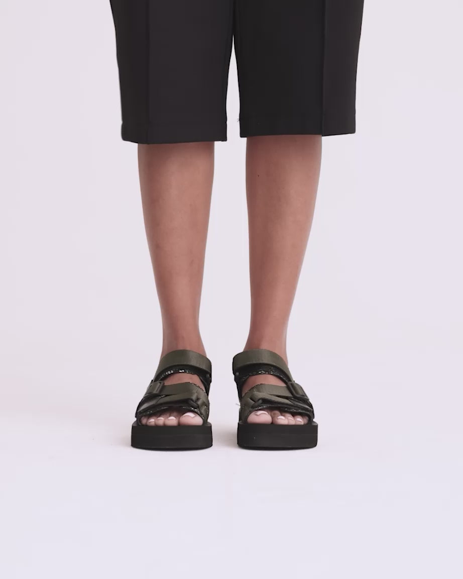 Load video: A pair of olive green nylon strappy sandals  with black padded soles.