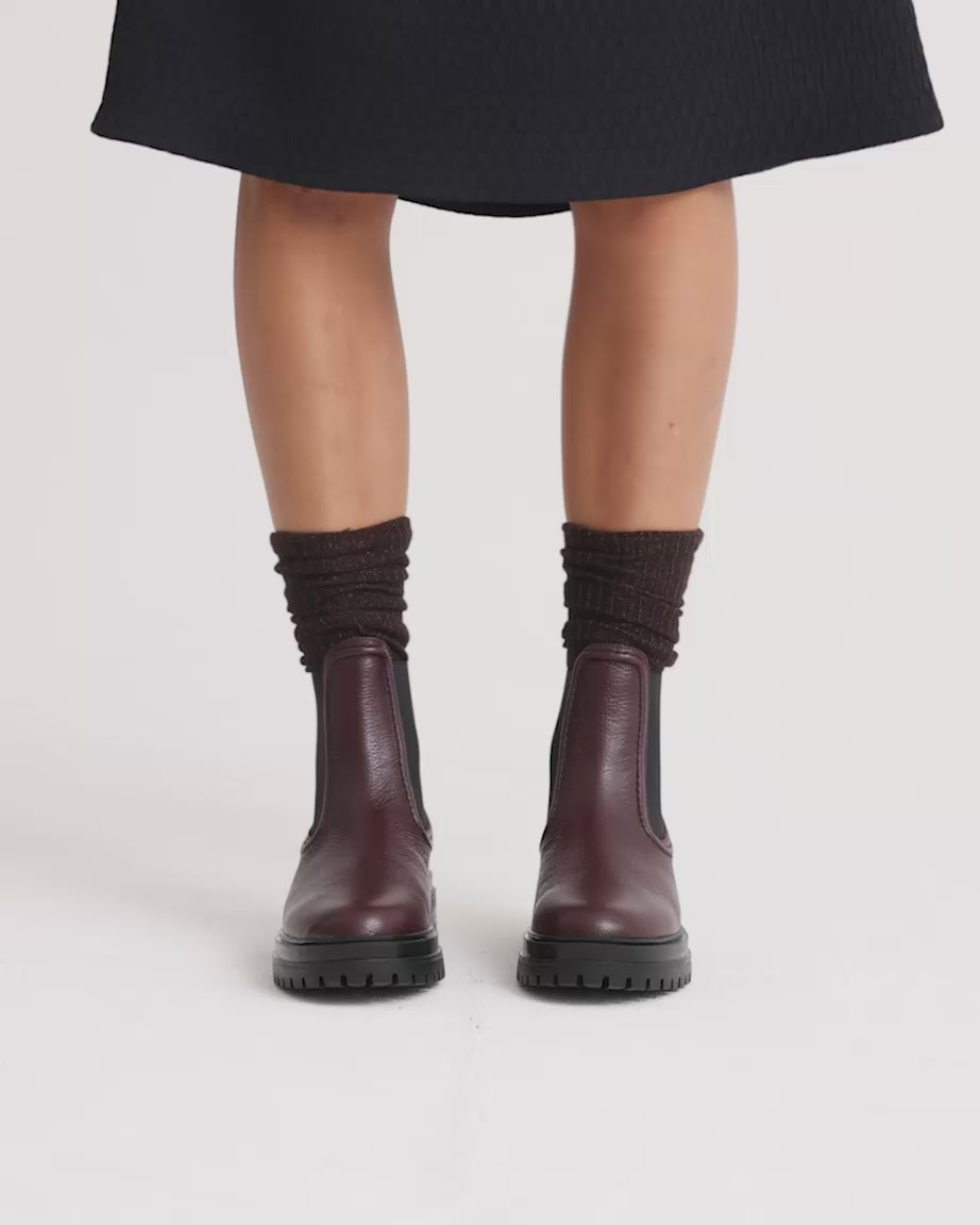Load video: Person wearing a black skirt, brown socks and purple boots with black soles